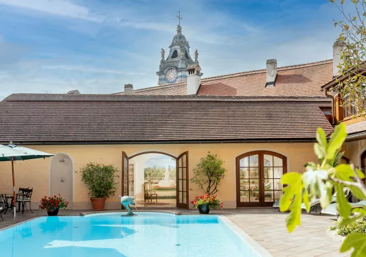 Outdoor pool with a small dolphin statue, and a clocktower in the background
