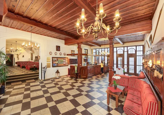 Hotel lobby with large wooden pillars and cushioned sofas over checkered flooring