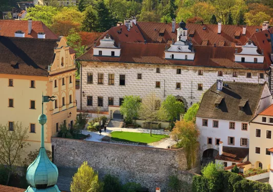 Exterior view of a white and brown hotel building with a small garden in front