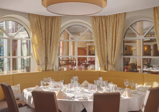 Circular table in a restaurant with wine glasses and folded handkerchiefs in front of each seat