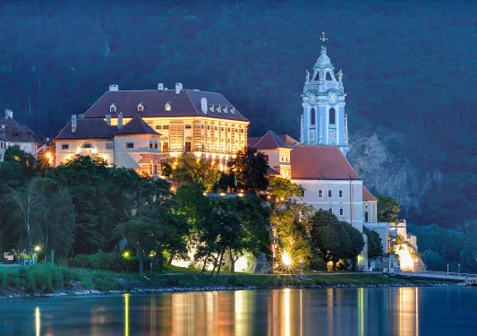 Exterior view of large hotel complex with a clocktower on the right, in front of a large lake