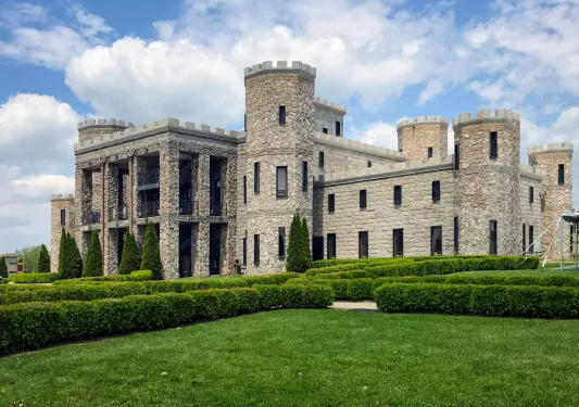Exterior view of a stone castle with a large lawn in front
