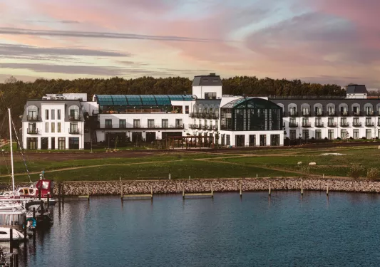 Exterior view of large, white building with outdoor balconies and large windows