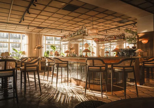 Indoor bar and lounge with tall stools and shelves holding bottles of liquor