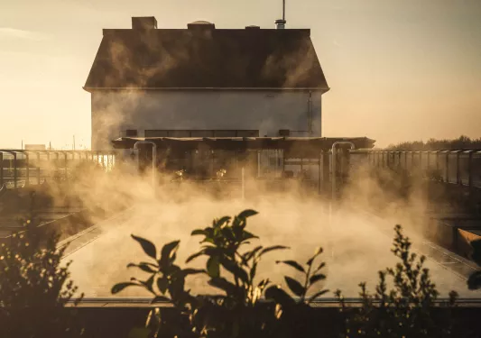 Outdoor pool with steam coming out with a large building in the background