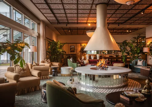 Lounge and seating area with cushioned chairs and a firepit in the center