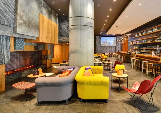 Lounge area with cushioned sofas next to large fireplaces