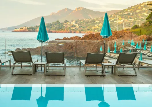 Outdoor pool with reclining chairs facing the ocean