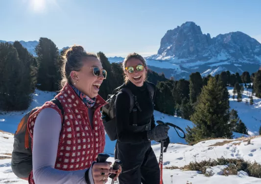 Two women smiling while hiking on a snowy valley