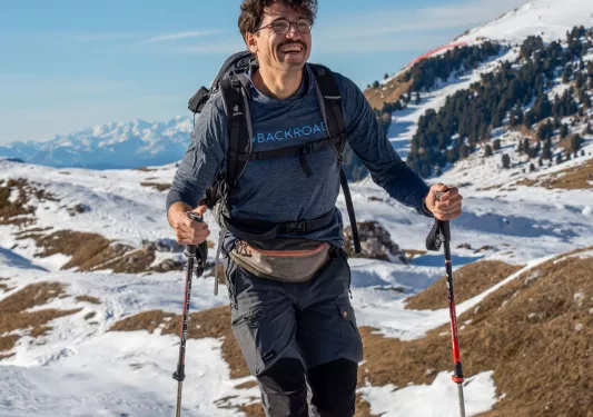 Man smiling while hiking in a snowy valley