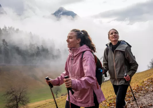 Two women hiking through a foggy valley