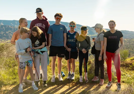 Large family standing and smiling on a hiking trail with the sunlight in the background