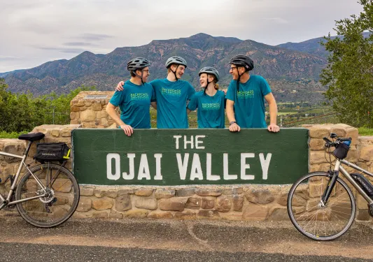 Four people standing behind a green Ojai Valley sign