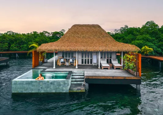Woman sitting in an outdoor pool outside of a cottage