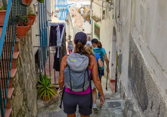 Group of women walking down an alleyway surrounded by stone apartments and houses