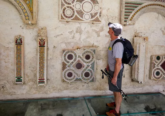 Man looking at stone art pieces on a building exterior