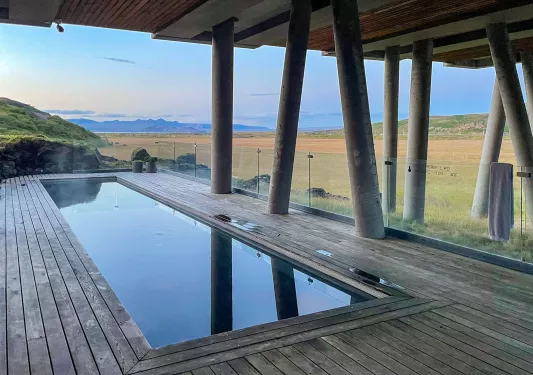 Outdoor pool under a bridge, with a large valley in the background