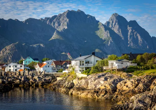 Houses by the ocean with large boulders and mountains in the distance