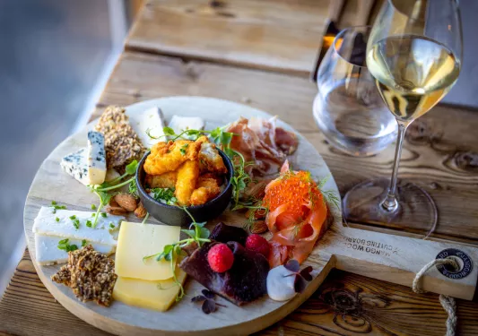 Wooden charcuterie board with sliced cheeses and cured meats