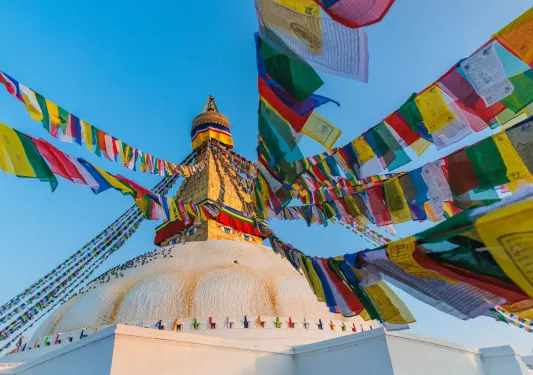 Top of stone building with a pillar statue and colorful paper on string