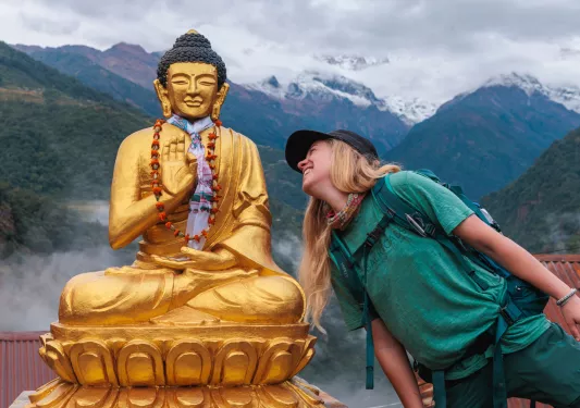 Woman smiling while leaning towards a Buddhist statue