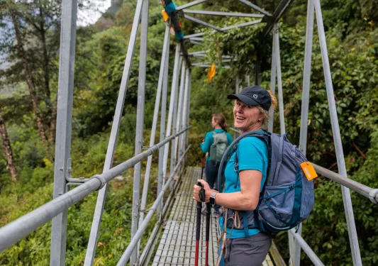 Woman looking back, smiling while walking on a wooden bridge