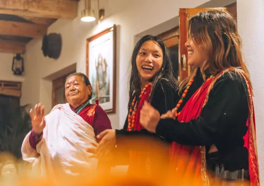Three women smiling while wearing traditional attire