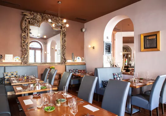 Restaurant dining area with long, wooden tables with gray chairs