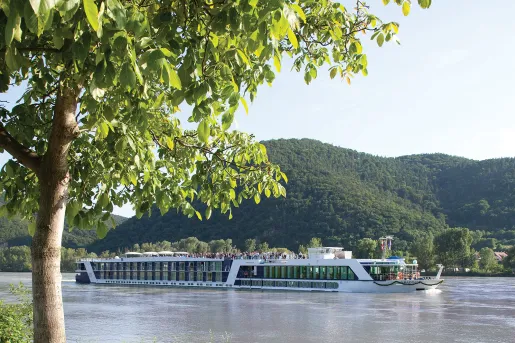 POV shot of AMA ship from riverside, floating down river.