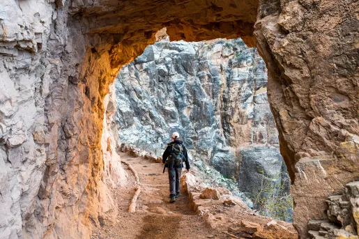Archway shot of guest hiking down trail, towards rock face.