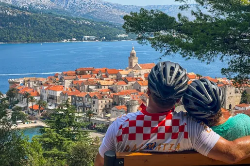Two guests in bike gear on bench, overlooking Dalmatian Coast.