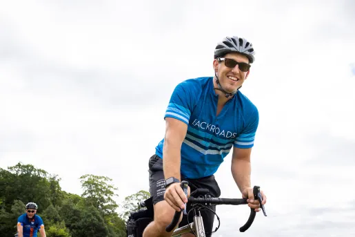 Ground-level shot of guest cycling, smiling at camera.