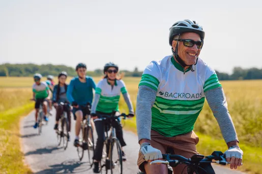 Close-up of line of cycling guests, golden meadow behind them.