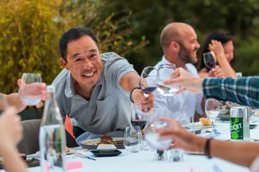 Guests at dinner table, cheersing wine glasses.