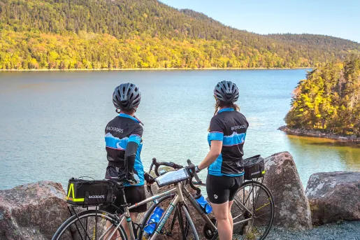 Two guests with bikes overlooking large body of water.
