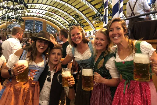 Four people in traditional German dirndels having pints of beer.