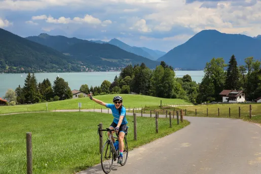 Biker riding on road with scenic German lake in background.