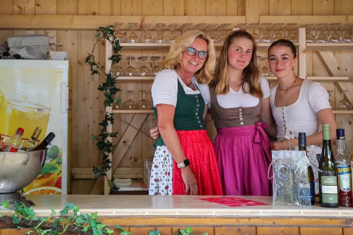 Three women posing together in traditional German dresses.