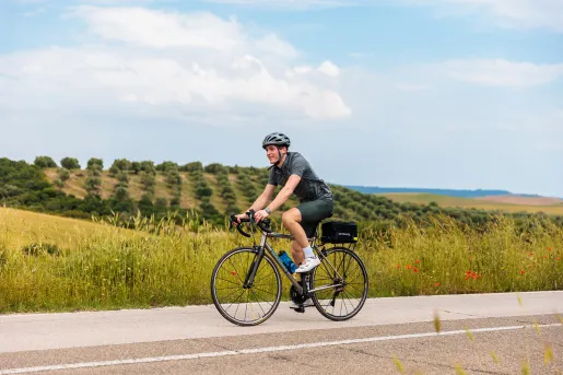 Guest cycling past grassy hills.