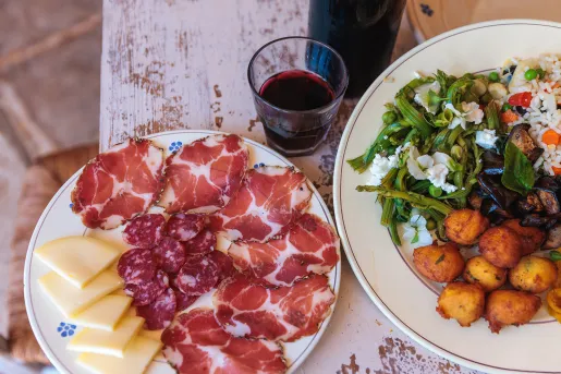 Two food platters, cheese, cured meats, rice and salads.