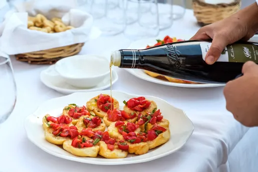Someone preparing bruschetta, pouring olive oil.