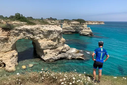 Guest overlooking white-rock coast, light blue water in background.