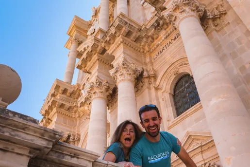 People smiling down from outside a church in Sicily