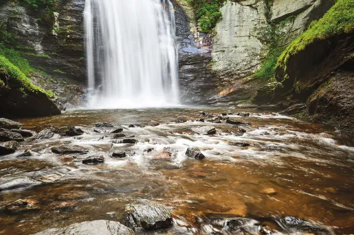 Shot of waterfall flowing into rocky stream.