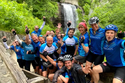 Group of guests in biking gear, waterfall behind them.