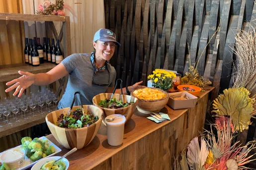 Leader behind lunch spread, gesturing to it.