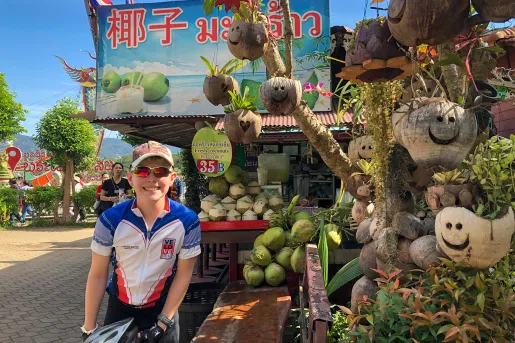 Backroads guest with a bike in front of a fruit stand in Thailand
