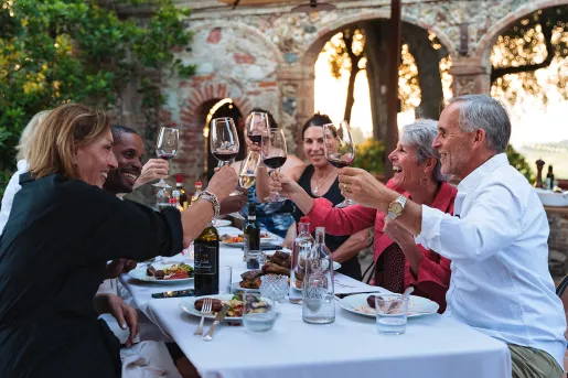 Group of guests at dinner, cheersing wine glasses.