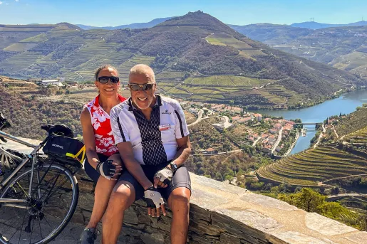 Two guests sitting on a stone wall overlooking the Douro River valley