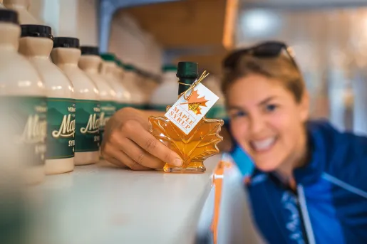 Guest holding maple syrup bottle to camera.